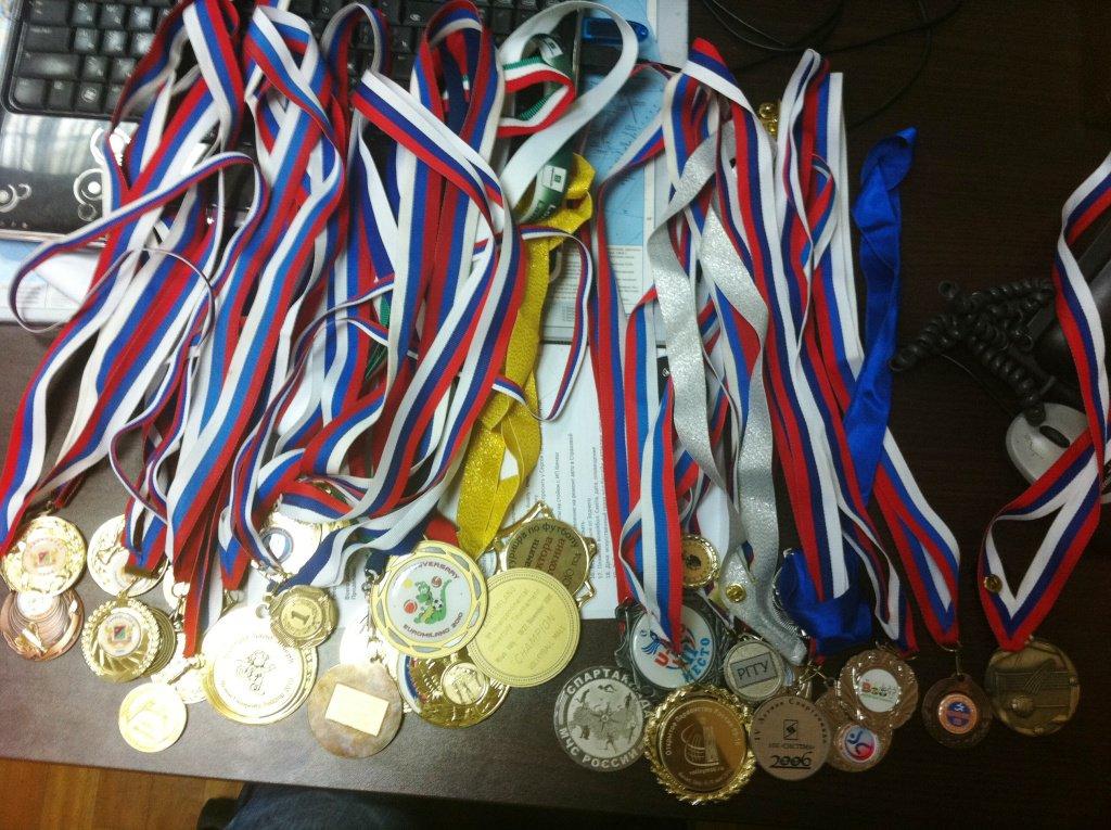 Призы спортсменам. Спортивные награды. Много медалей. Спортсмен с медалью. Много спортивных медалей.